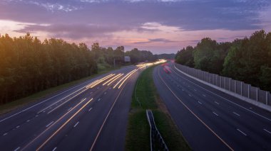 Ağaçların üzerinde gün doğumu sabah trafiğinin yoğun olduğu otoyol üzerindeydi. İki yönde de trafik vardı. Arabalardan sarı ve kırmızı ışık çizgileri çiziyorlardı.