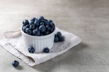 Tahta bir masanın üzerinde beyaz bir tencerede bir sürü taze yaban mersini..