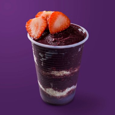 Plastik bardakta Brezilya dondurması, çilek ve yulaf ezmesi. Mor arka planda izole. Yaz menüsü ön görünümü.