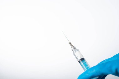 Elleri mavi eldivenli, elinde aşı olan bir şırınga var. Covid-19 koronavirüs. beyaz arkaplan.