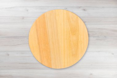 Yuvarlak ahşap mutfak tahtası, ahşap masa arkasında izole edilmiş. Üst görünüm.