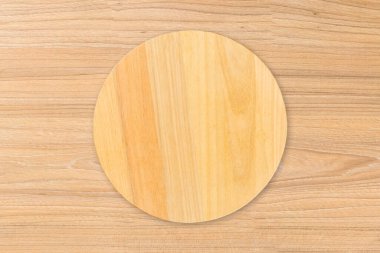 Yuvarlak ahşap mutfak tahtası, ahşap masa arkasında izole edilmiş. Üst görünüm.