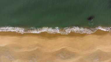 Kumsaldaki yumuşak su sıçratan dalgaların yukarıdan görünüşü.