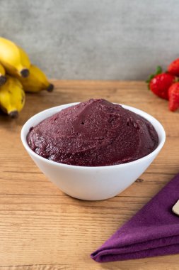 Acai, elinde Brezilya dondurması kasesi olan bir kadın. Ahşap arka planda meyveler. Yaz menüsü ön görünümü