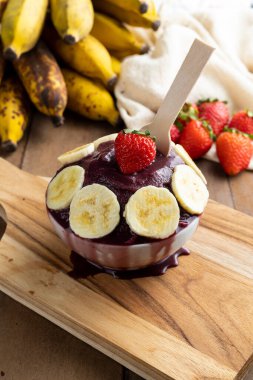 Acai, elinde Brezilya dondurması kasesi olan bir kadın. Ahşap arka planda meyveler. Yaz menüsü ön görünümü