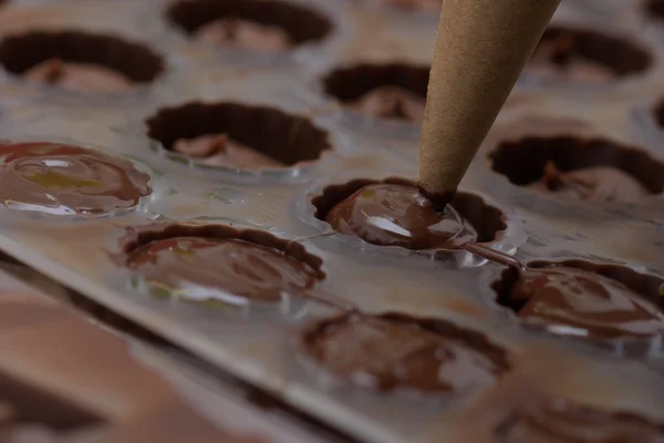 Verser du chocolat dans des moules métalliques — Photo