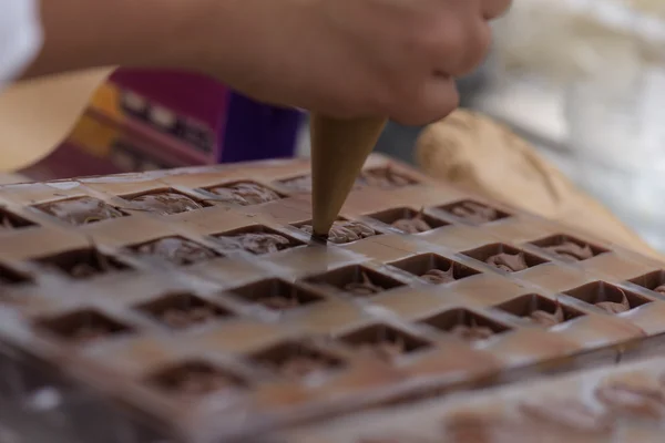 Despejar chocolate em moldes de metal — Fotografia de Stock