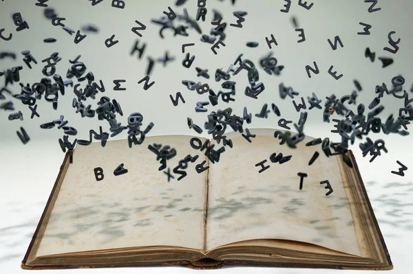 Letters of the alphabet in levitation in the air over the open book