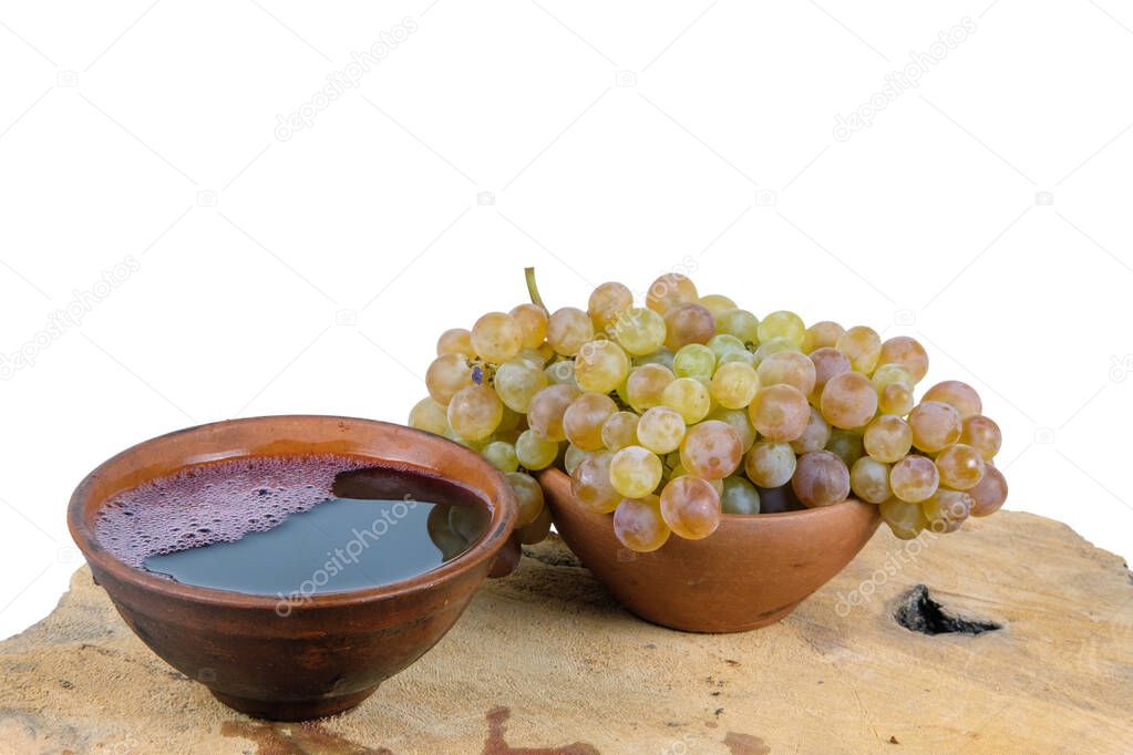 Georgian traditional decorative clay cups for wine with grape on the wooden log slice with isolated background