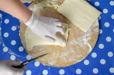 Bir şefin elleri ahşap kesme tahtasındaki hamurda peynir pişiriyor. 