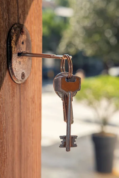 Set of keys on the ring in the keyhole with blurred street background, selective focus