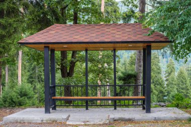 Kırsal otobüs durağında arka planda orman var.