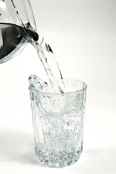 Pouring drinking clean water from a pot into a glass on a white background