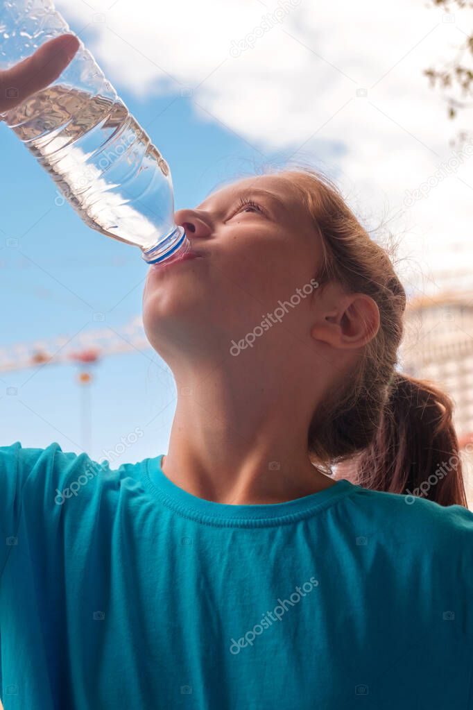 A girl in blue shirt drinking water from the bottle
