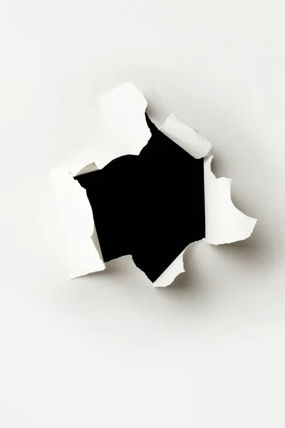 Beyaz kağıtta yırtılmış delik, içinde siyah arka plan var.