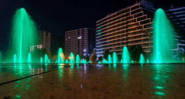 Mimari arka planlı dans eden renkli fıskiyelerin gece manzarası