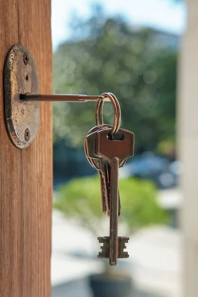 Set of keys on the ring in the keyhole with blurred street background, selective focus