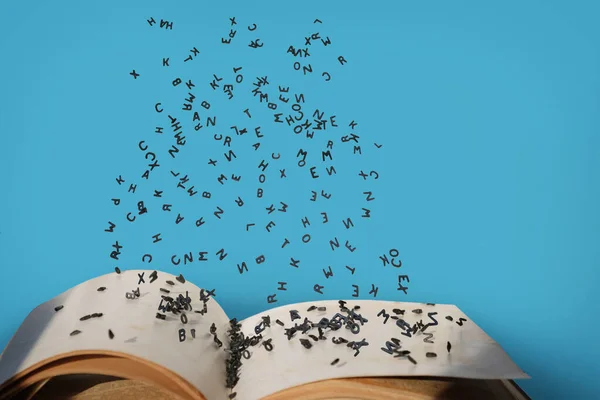 Letters of the alphabet in levitation in the air over the open book pages