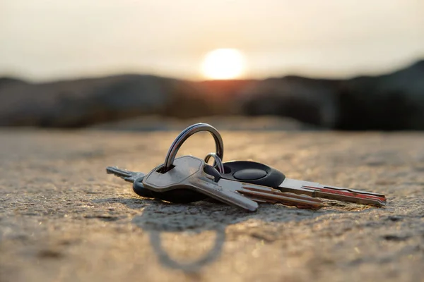A lost keys on the ring on the rock illuminated with sun rays, blurred sunset background selective focus