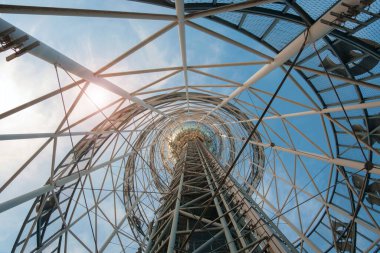 Gökyüzü arka planında büyük metal mimari yapı, aşağıdan görünüm