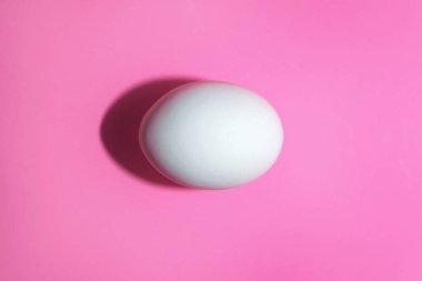 Pembe bir yüzey üzerinde beyaz çiğ yumurta.