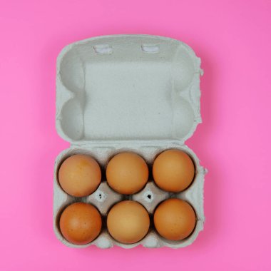 Pembe bir yüzey üzerinde kağıt tepside kahverengi yumurtalar