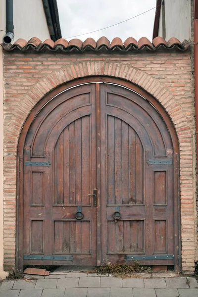 大きな丸金属ハンドルとタイル張りの屋根を持つ古い木製の門 — ストック写真