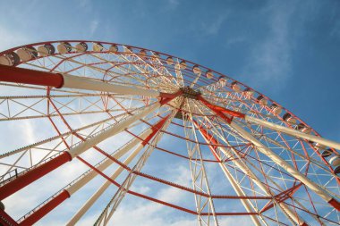 Mavi gökyüzüne karşı büyük kırmızı ve beyaz dönme dolap.