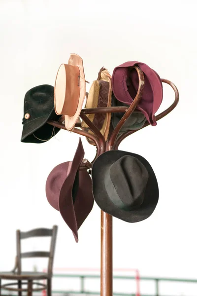 各种各样的老式彩色帽子挂在木制棕色衣架上 — 图库照片