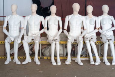 Kadın ve erkek, merdivende oturan beyaz plastik mankenler. 