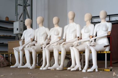 Kadın ve erkek, merdivende oturan beyaz plastik mankenler. 