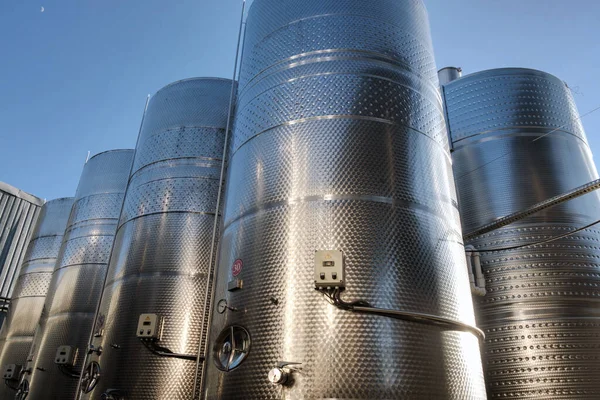 Stainless tanks for processing and fermentation wine production in the open air with blue sky background. Modern wine factory