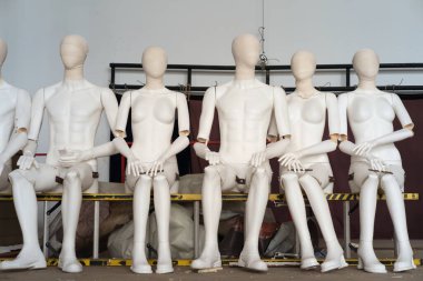 Kadın ve erkek, merdivende oturan beyaz plastik mankenler. 