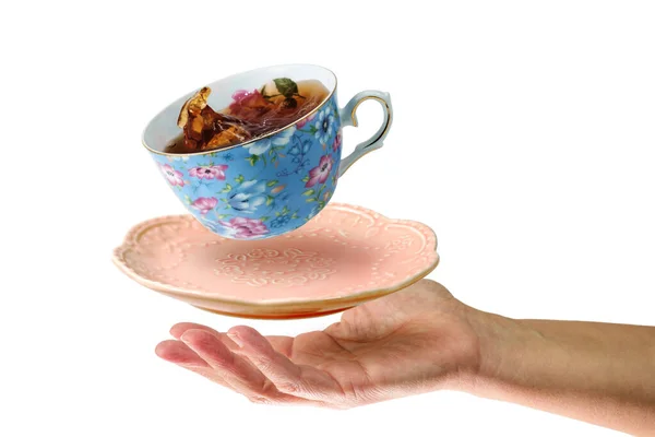 Левитация Голубой Чашки Чаем Розовой Тарелкой Над Женской Рукой Изолированный — стоковое фото