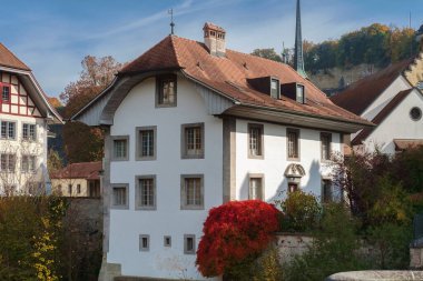 Old white house with autumn red tree 