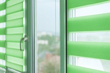 Penceredeki renkli kumaş jaluzileri kapatın. Perdeleri açın..