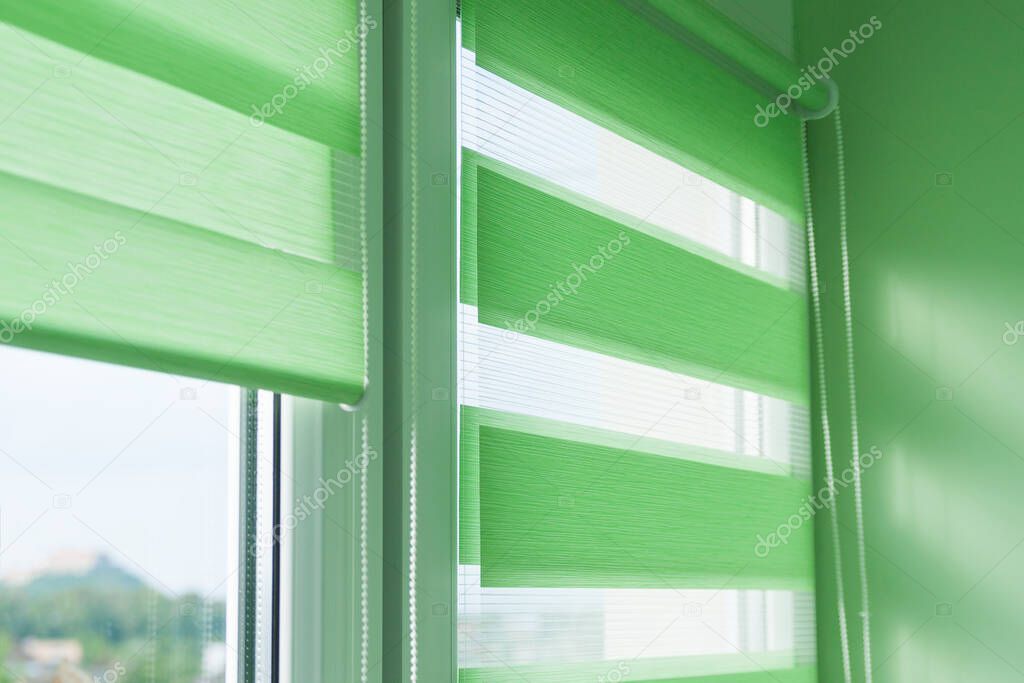 Close up of colored fabric roller blinds on window. Roll curtains.