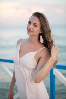 Gün batımı sahilinde genç, zayıf, güzel bir kadın.