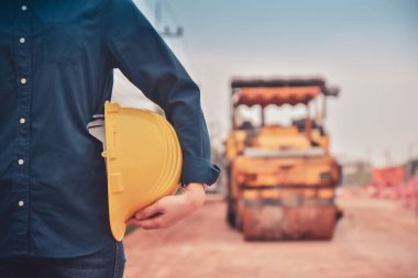 Close up hand holding helmet hard hat Engineering concept, Worker Engineer Standing on road site construction