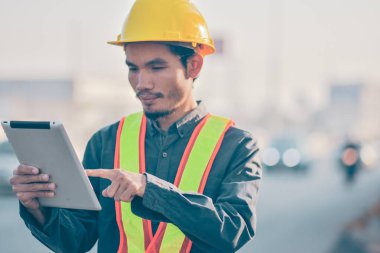 Asian man Engineer worker use tablet checking work on site road construction