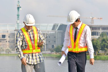 İki Mühendis planlarını elinde tutarak tartışmalı gayrimenkul projesini konuşuyor.
