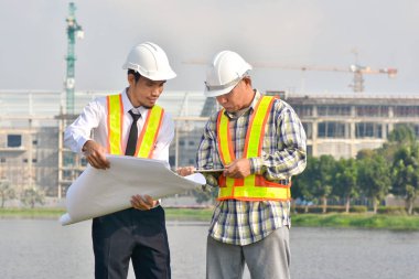 İki Mühendis planlarını elinde tutarak tartışmalı gayrimenkul projesini konuşuyor.