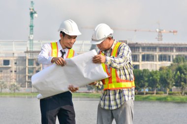 İki Mühendis planlarını elinde tutarak tartışmalı gayrimenkul projesini konuşuyor.