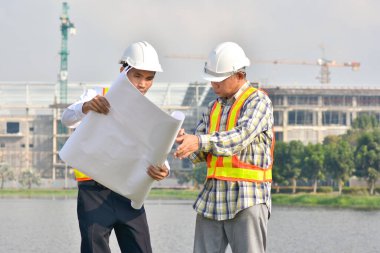 İki Mühendis planlarını elinde tutarak tartışmalı gayrimenkul projesini konuşuyor.