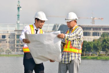 İki Mühendis planlarını elinde tutarak tartışmalı gayrimenkul projesini konuşuyor.
