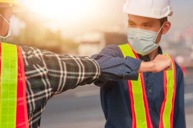 İki mühendis ve tıbbi maske merhaba de. Dokunmak yok. Koronavirüsü koru.