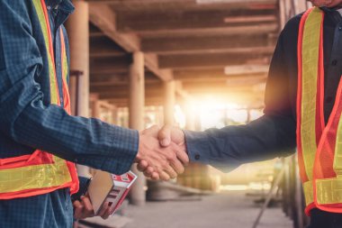 İnşaat alanında iki mühendis el sıkışıyor.