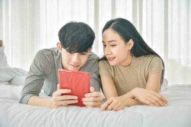 Yatak odasında tablet kullanan Asyalı çift