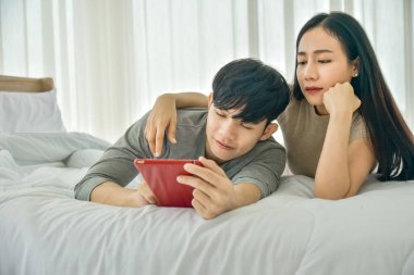 Yatak odasında tablet kullanan Asyalı çift