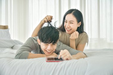 Yatak odasında tablet kullanan Asyalı çift